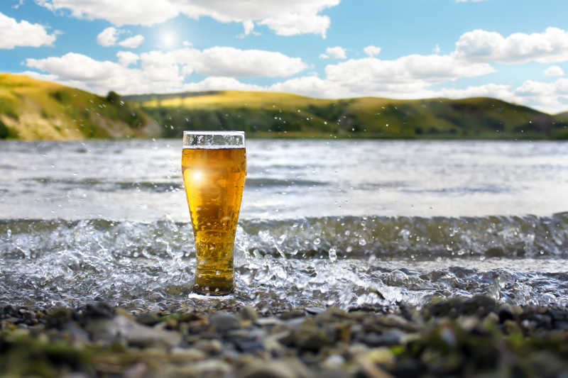 日落的海边的一杯冰凉啤酒