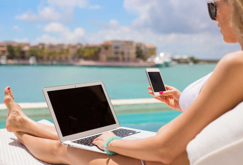 看着笔记本电脑的美女在海边沙滩上