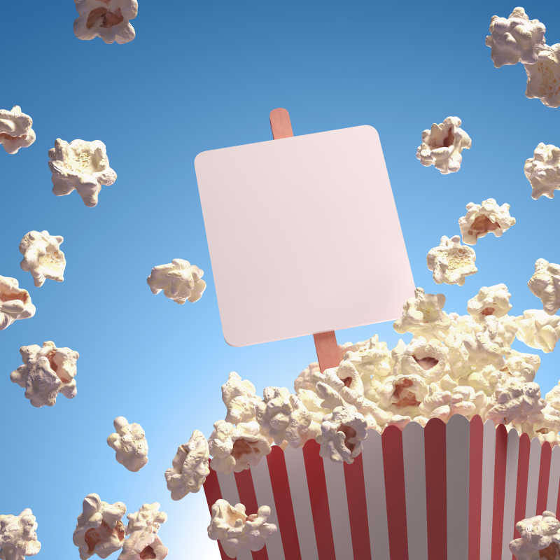 蓝色背景下白色的直板插在条形纸杯的爆米花内