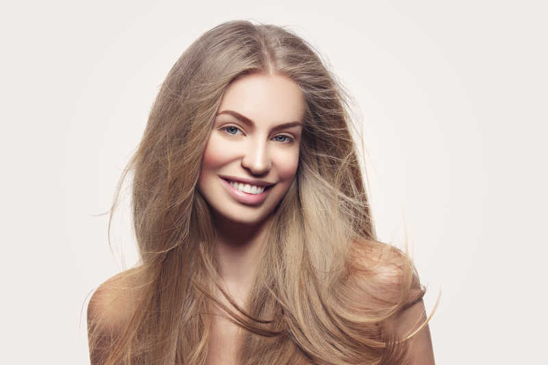 白色背景下微笑的金色长发美女