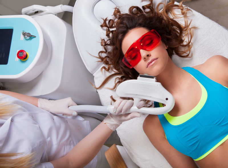 戴着红色护目镜接受面部护理的美女