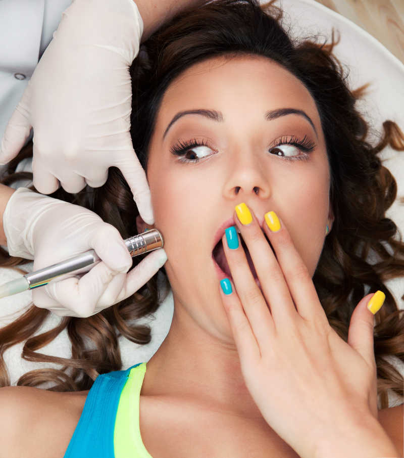 接受面部激光脱毛治疗的美女惊讶的表情