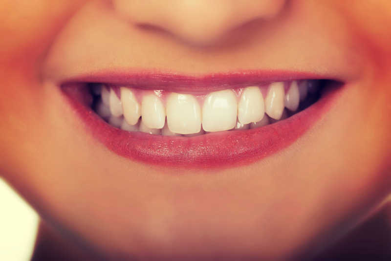 美丽的女人在使用牙线清洁她的洁白的牙齿