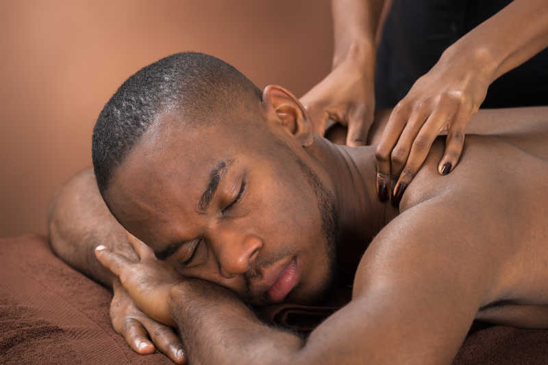 正在做颈肩按治疗的非洲男青年