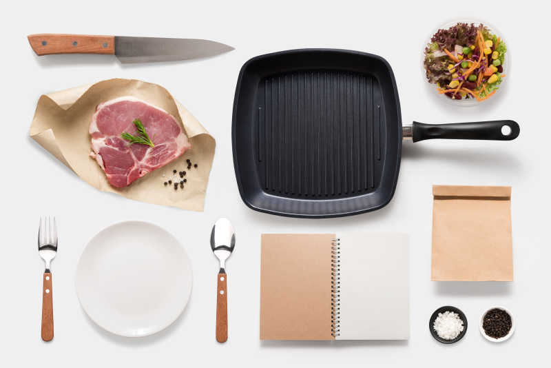 白色背景下生肉与烤肉餐具