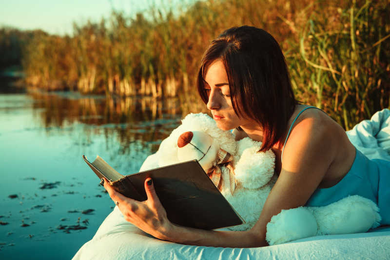 女孩躺在漂浮的床上看书