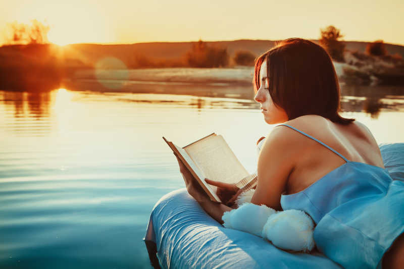 躺在漂浮的床上看书的美丽女孩