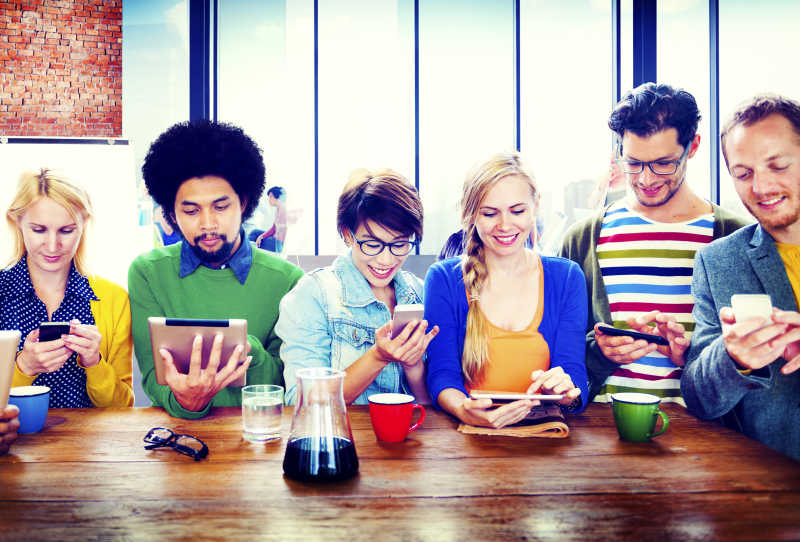 聚会上一群年轻人正在玩电子通讯设备