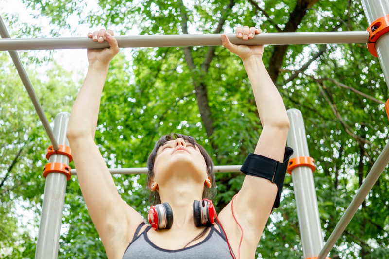 穿着黑色内衣美女正带着耳机在单杠下