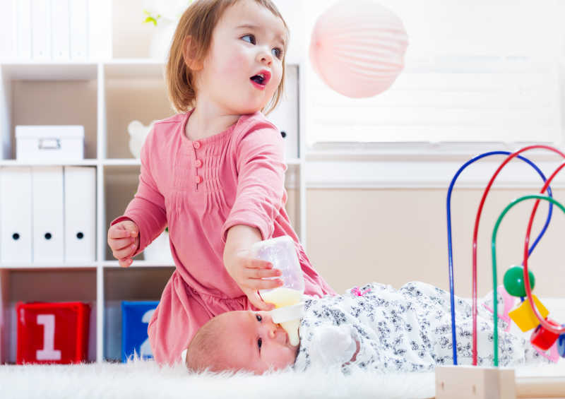 给新生婴儿妹妹喂奶的小女孩