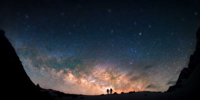 两个人站在一起双手捧着山上的银河