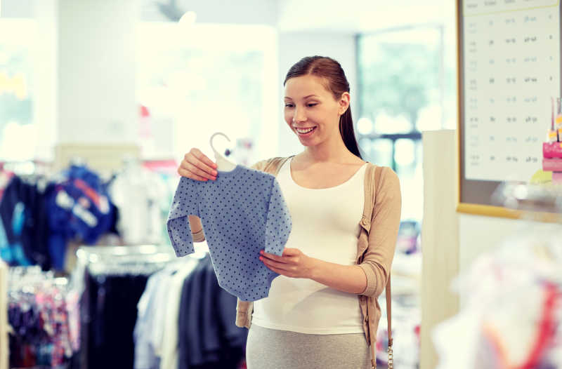 认真挑选婴儿服装的孕妇