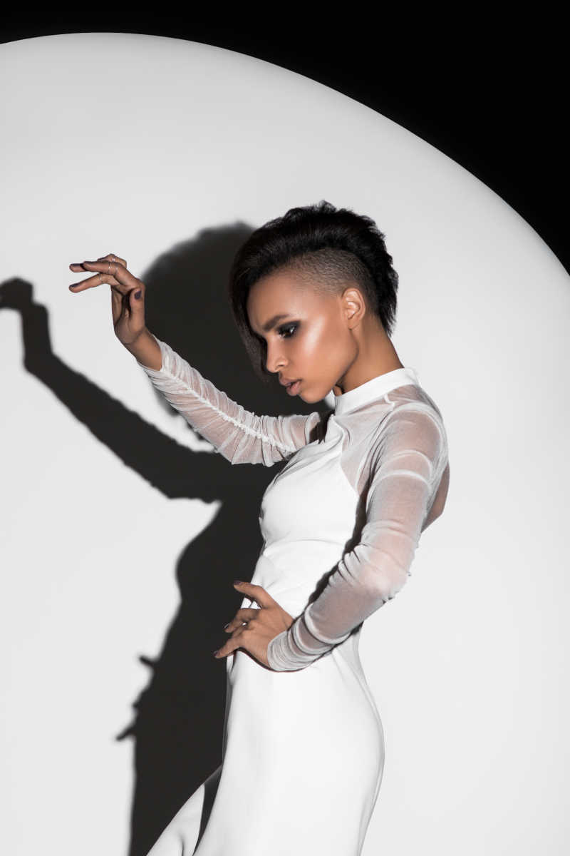 穿着白色的衣服的魅力时尚的性感模特的手摆着姿势