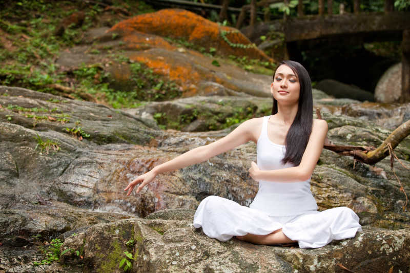 美丽的亚洲女子在户外天然林练习瑜伽