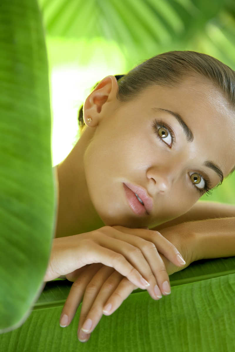 美丽的热带植物叶子后的美丽女人