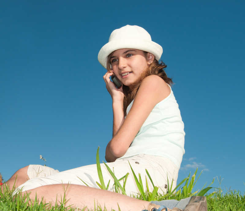 可爱的度假中坐在草地上的女孩