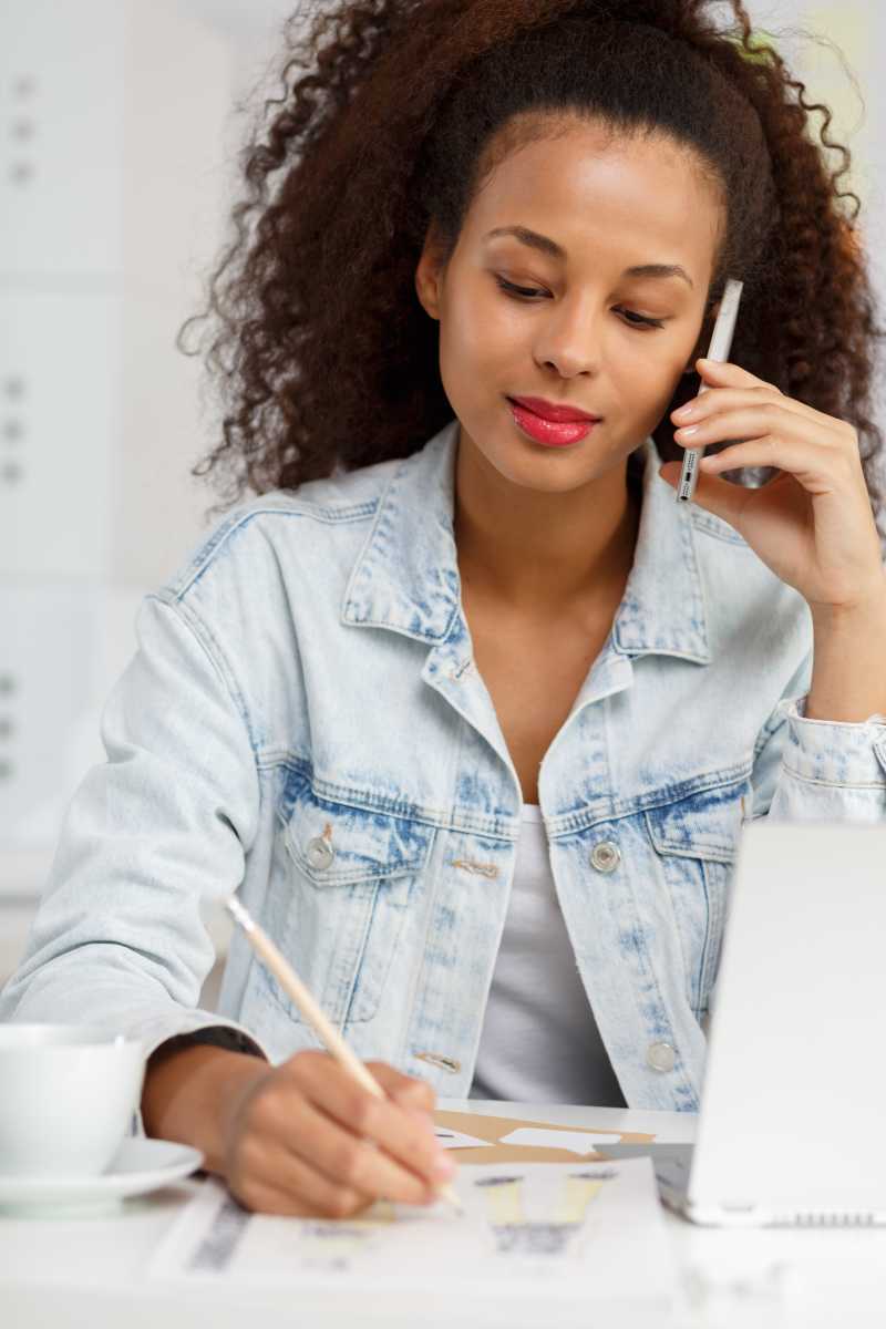 坐在桌子前一边打电话一边工作的美女设计师