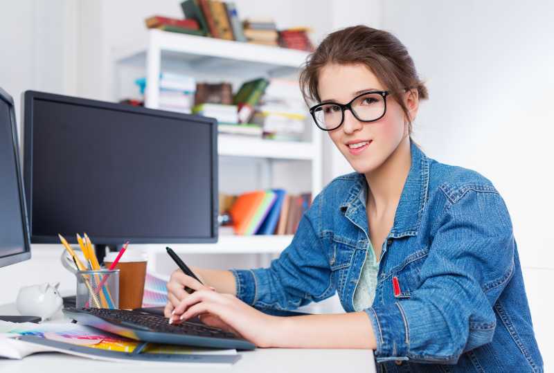 坐在办公桌前带着黑边眼镜微笑的美女