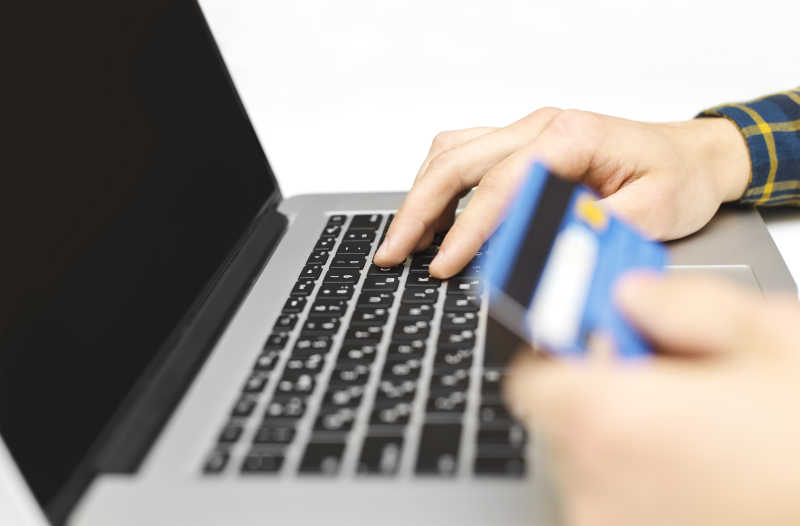 手拿银行卡在笔记本上输入