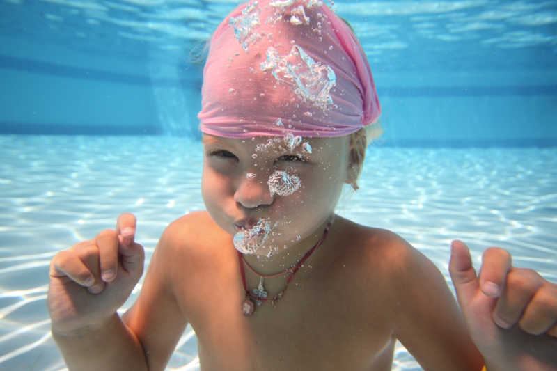 在游泳池里水下睁着眼睛潜水的女孩