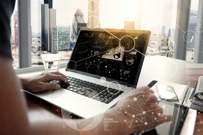 面向阳光照射的办公桌和使用笔记本电脑的商人