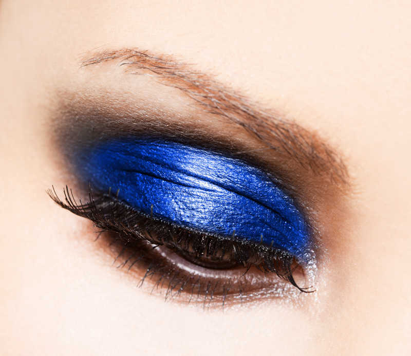 涂着蓝色眼影和粘着假睫毛的美女的眼睛特写