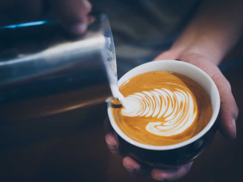 杯子里的牛奶倒入咖啡中制作拉花拿铁咖啡瞬间摄影