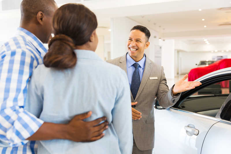 汽车经销商微笑着给客户介绍