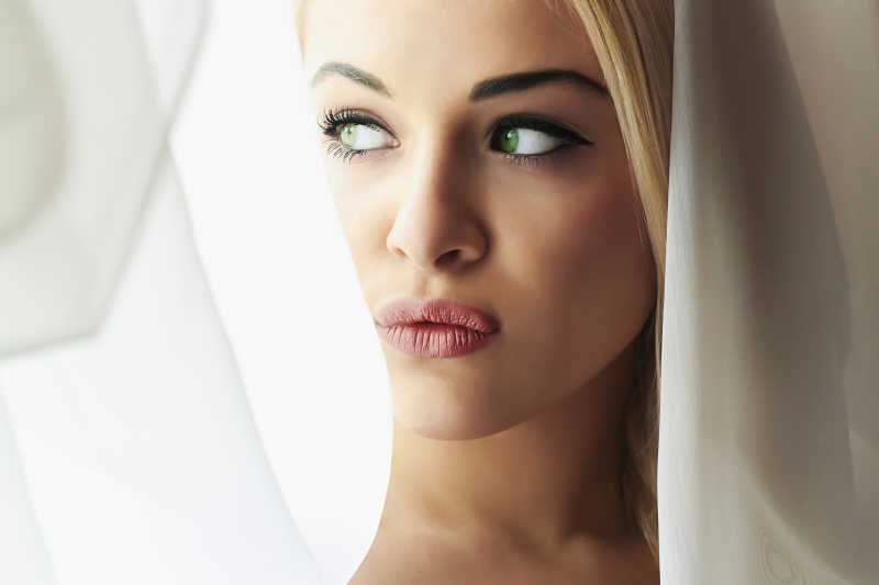 在窗帘边噘嘴的女孩