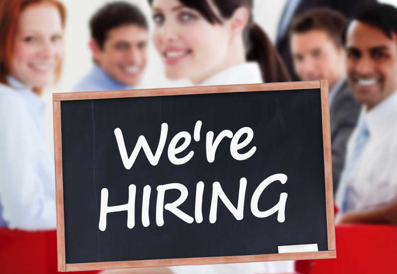 商人和写着我们正在招聘的黑板