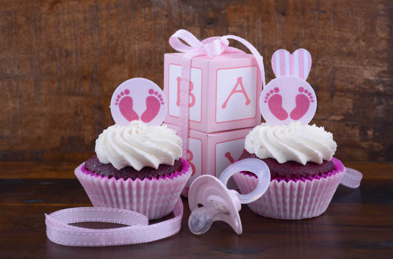 木制背景上的婴儿用品和蛋糕