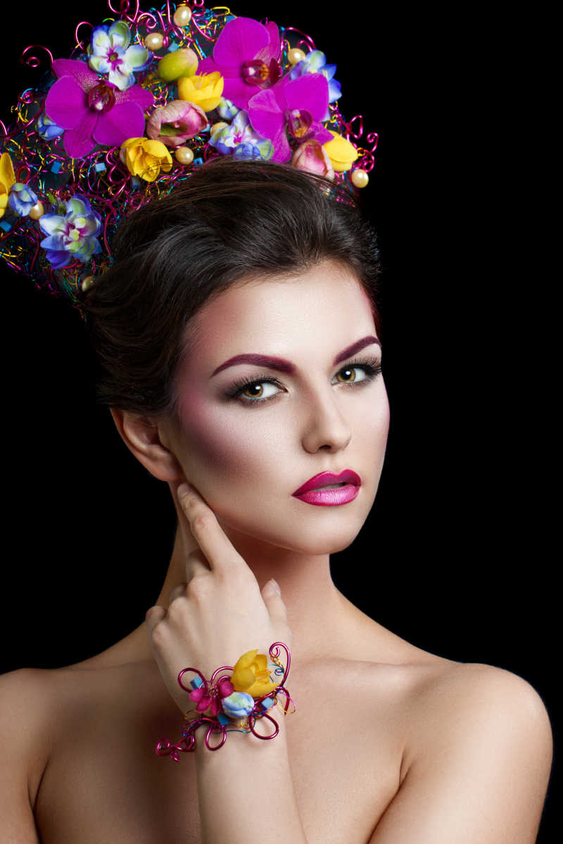 黑色背景下带着鲜花的美丽的年轻女人