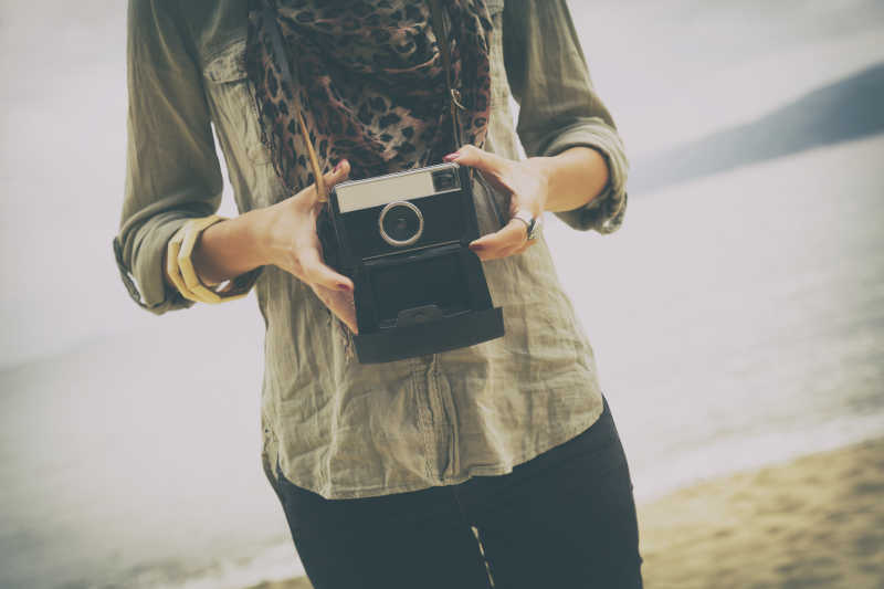 海滩边戴着照相机照相的美女