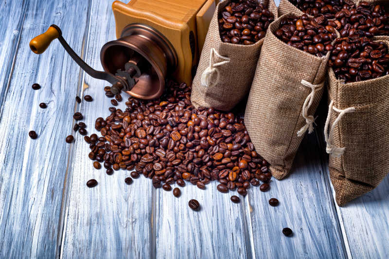 木桌上散落的咖啡豆和咖啡磨碎机