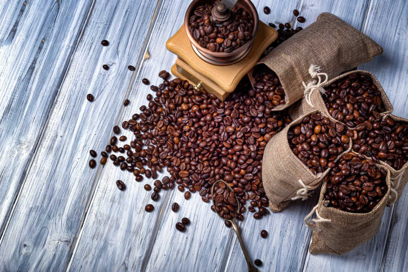 木桌上装满咖啡豆的小麻袋和咖啡碾磨机