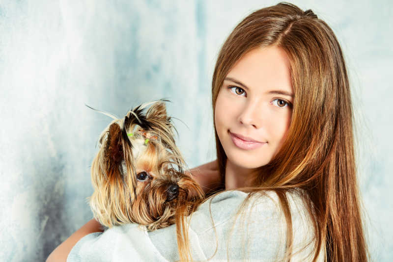 年轻的金发女孩抱着她的宠物狗