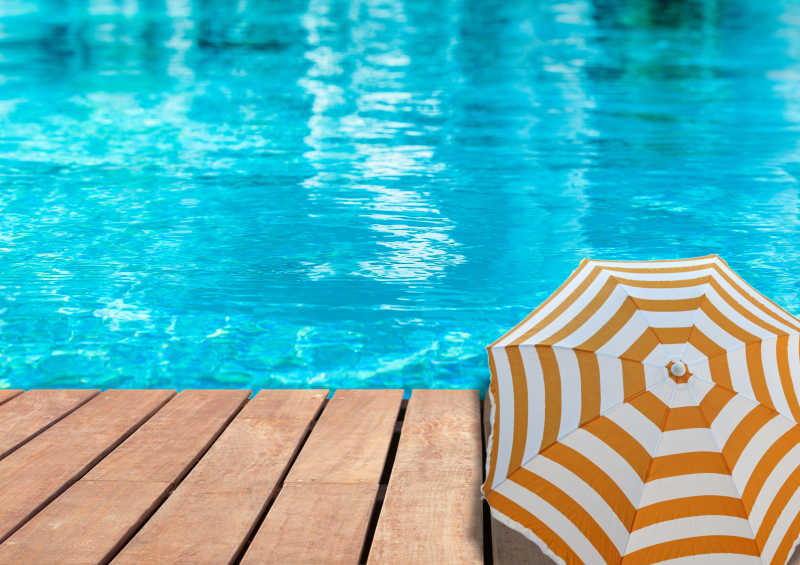 游泳池背景上有木制平台和太阳伞