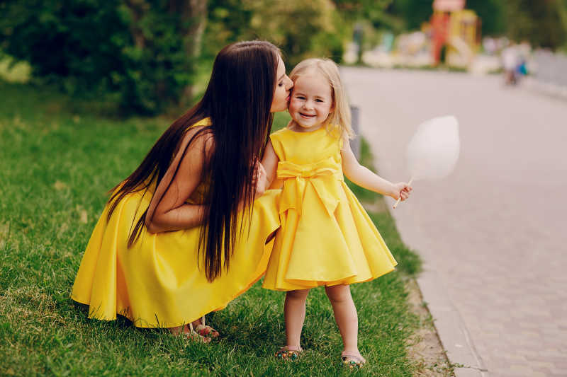 母亲亲吻拿着棉花糖的女儿