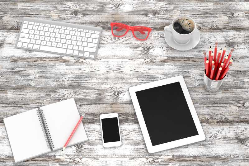 木桌上的键盘ipad智能手机等办公用品