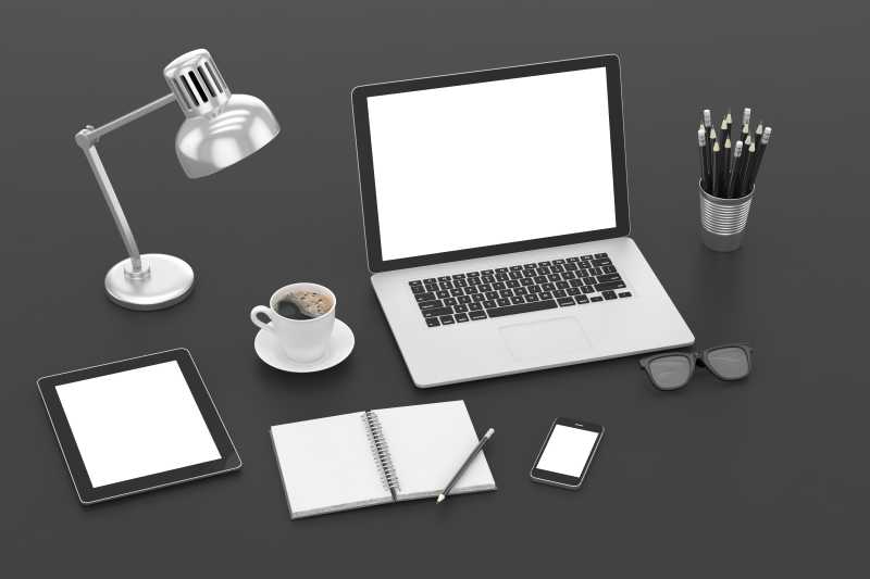 灰色桌面上摆放的笔记本电脑台灯笔筒iPad等办公用品