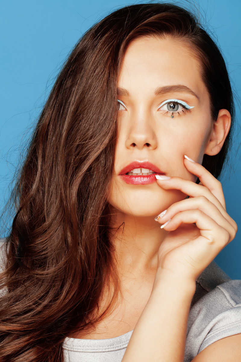 蓝色背景下长发的时尚美女