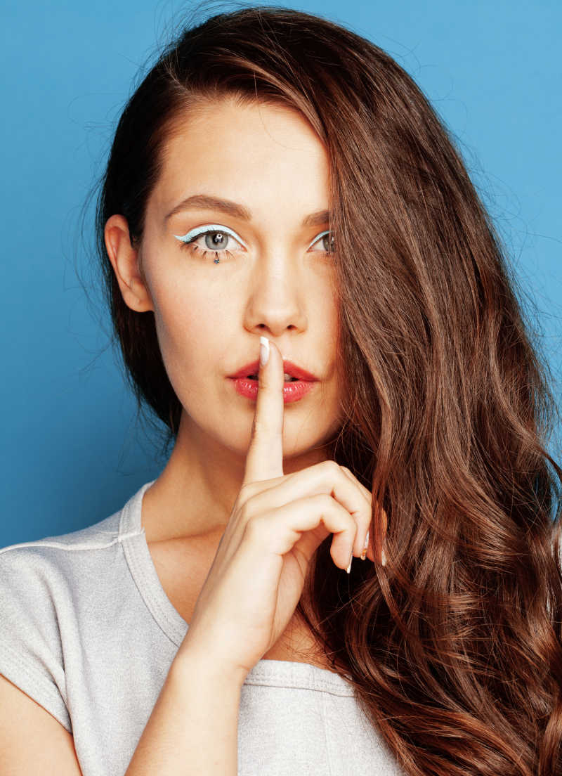 蓝色背景下举着手指的长发女人