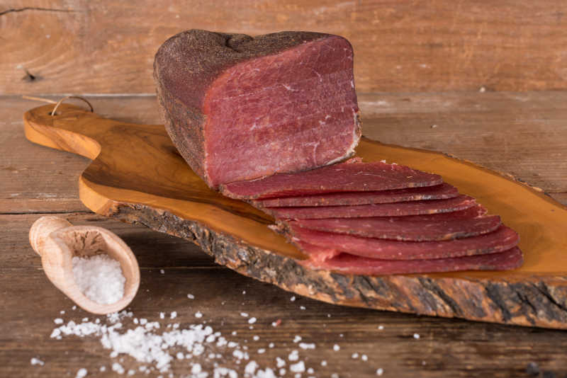 木板上的白色盐粒和砧板上切好的熏肉