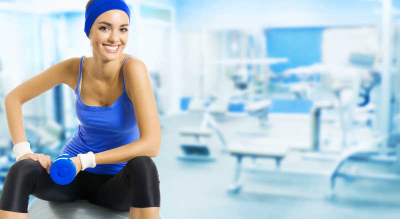 健身房里拿着蓝色哑铃的女人