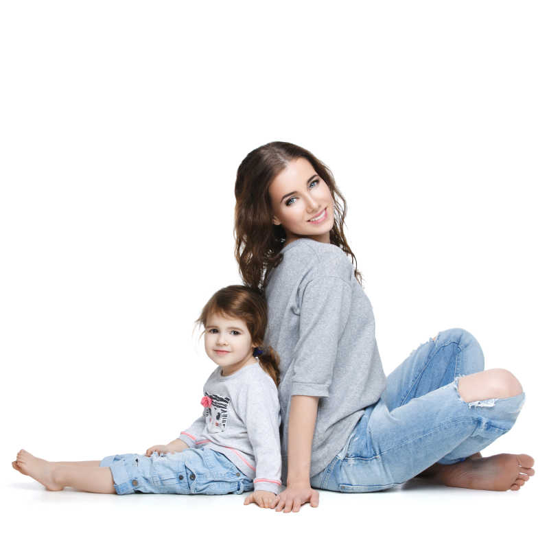 在白色背景下时尚妈妈与女儿背靠背