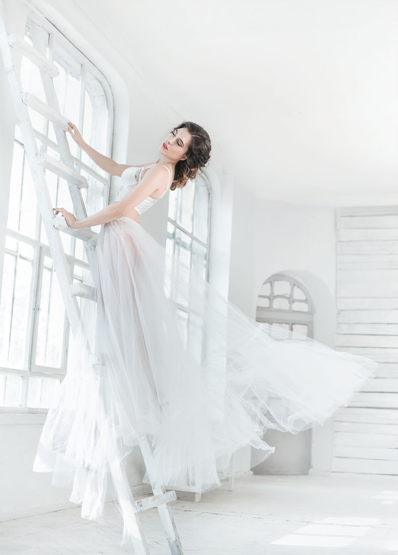 站在梯子上穿白纱裙的外国美女