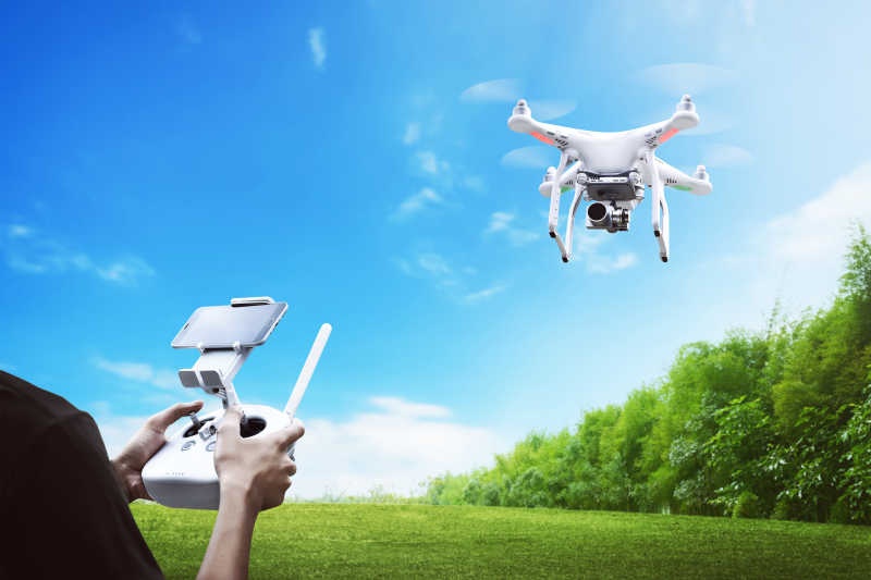 在草地上使用遥控器操控无人机飞行