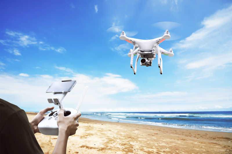 在海边沙滩上用遥控器操控无人机飞行