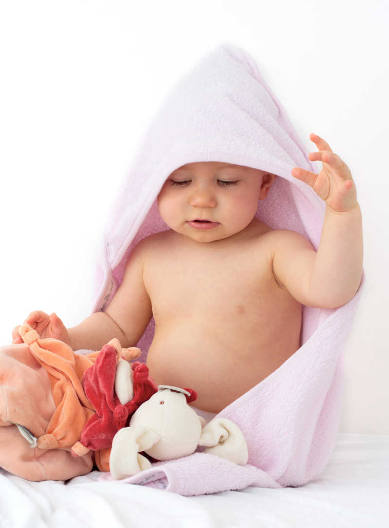 披着红色毛毯玩玩具的婴儿