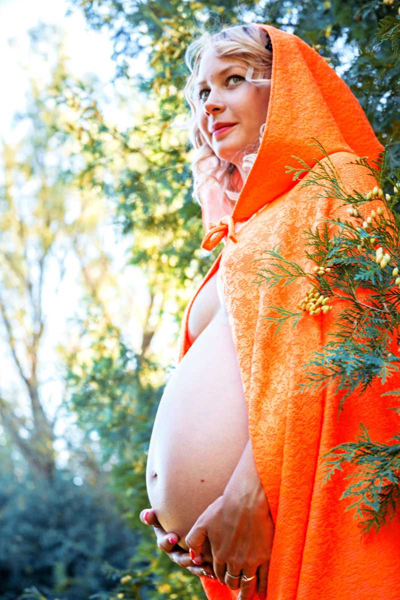 树边披着斗篷的金发孕妇